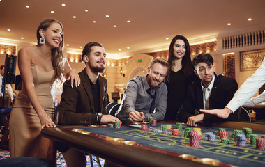 Group of friends enjoys winning poker roulette in a casino.