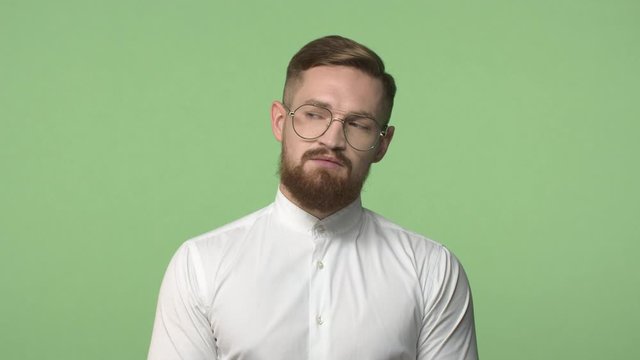 Slow-motion bossy, serious-looking bearded man, office manager in glasses, looking around with busy stricts expression, searching something, turn head sideways left and right, green background