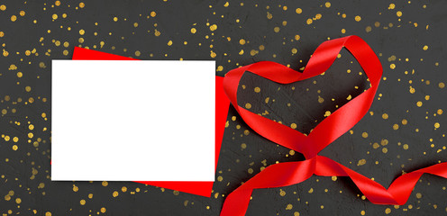 Mock up greeting composition for Valentines day or wedding.. Empty paper blanks, red ribbon heart on black background with golden confetti. Mothers day or Women day concept. Copyspace.