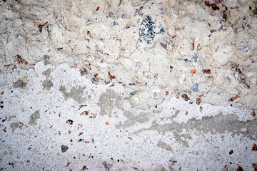 Concrete wall with signs of aging. Colored stones and drops on a light construction background.