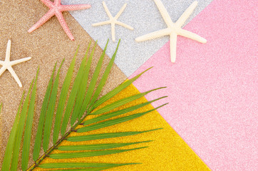 Fototapeta na wymiar Flat lay summer vacation. Palm leaf and starfishes on a geometric shiny background