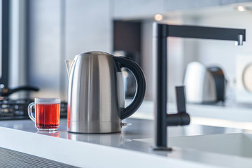 Electric kettle for boiling water and making tea on a table in the kitchen interior. Household...