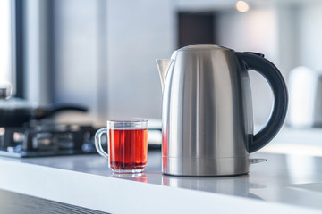 Electric kettle for boiling water and making tea on a table in the kitchen interior. Household...