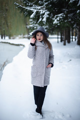 Fototapeta na wymiar Girl in a gray coat in a winter snow park