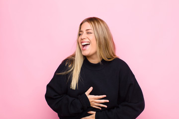 young blonde woman laughing out loud at some hilarious joke, feeling happy and cheerful, having fun...