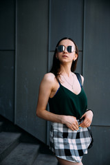 Obraz premium Sexy girl near a dark wall in a T-shirt, sunglasses and short shorts