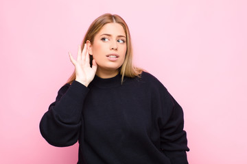 young blonde woman looking serious and curious, listening, trying to hear a secret conversation or...