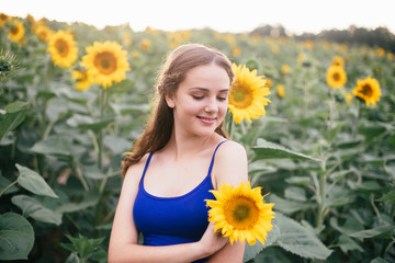 Beautiful girl on the field with sunflowers in short shorts and a vest