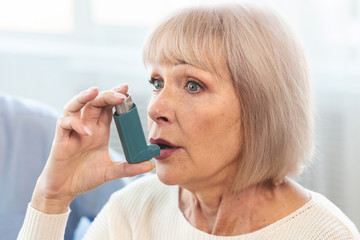 Elderly woman using asthma inhaler for allergies