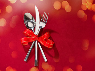 Fork and knife in spoon tied with red ribbon on red cover. ackgrounds for special days ( Valentine's Day, Wedding anniversary, birthday. dating, Christmas, New Year and Mother's Day )
