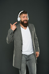Look at my headset. Hipster point finger at headset grey background. Bearded man listen to music...