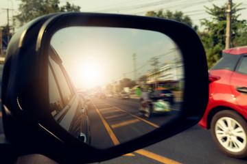 Side view of car mirror traffic of rear-end vehicles on the road with sunlight. 