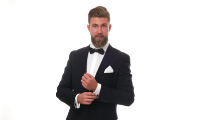 Good looking young man with beard wearing classic black suit, isolated on white background.