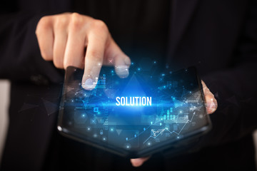 Businessman holding a foldable smartphone with SOLUTION inscription, business concept