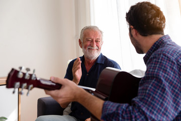 Obraz premium Smiling Senior Father sing a song with Adult Son on sofa at home.