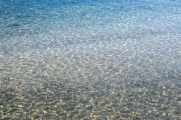 Crstal clear water of the adriatic sea, beach shot. Small white and blue waves on a rocky pebble beach