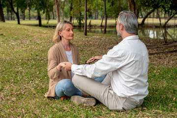 Fototapeta premium Happy senior Caucasian couple are doing meditation in park. Lovely elder couple concept