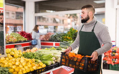 Obraz premium Supermarket employee carries a box of oranges