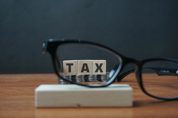Tax concept with wooden blocks on stacked coins