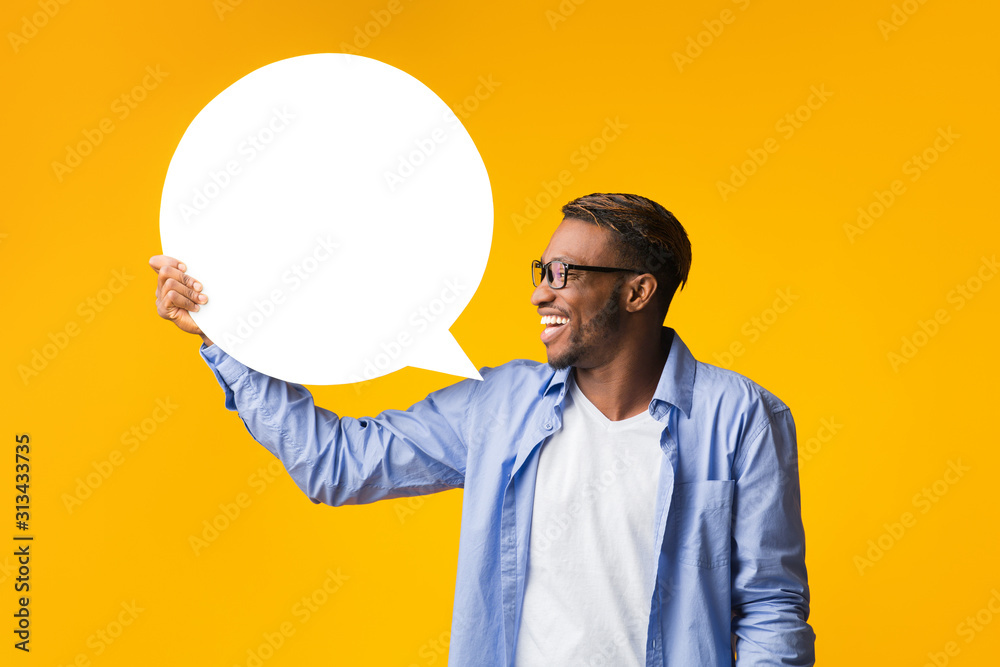 Wall mural Happy Afro Guy Holding Blank Speech Bubble Standing, Yellow Background