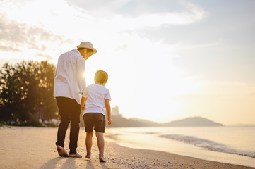Family, travel, beach, relax, lifestyle, holiday concept. Father and his son who enjoy a picnic and sea bathing at the beach on sunset in holiday.