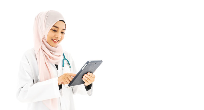 Portrait of beautiful young Muslim woman doctor using digital tablet computer, standing isolated on white background