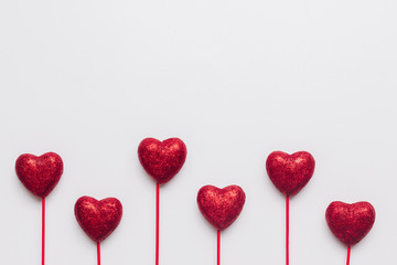 Stock photo of red hearts with red stick on a white background and a space for text