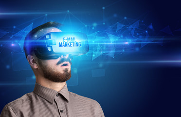 Businessman looking through Virtual Reality glasses with E-MAIL MARKETING inscription, cyber security concept