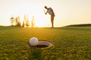 lifestyle, golf, activity, outdoor, sport, golfer concept. Golf balls that are going to be hole by golfers at the green grass golf course at sunset. - Powered by Adobe
