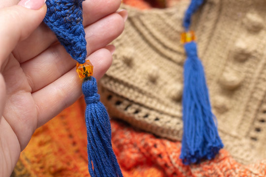 knitted scarf on the neck, bactus. in hand a part of a scarf with a bead
