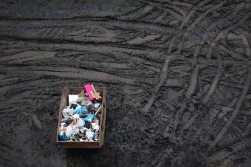 Trash in a large container, top view, dirt background
