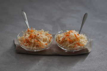 Sauerkraut with carrots and cumin in a jar on a linen napkin with a wooden spoon in a rustic style on a dark background