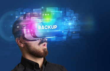 Businessman looking through Virtual Reality glasses with BACKUP inscription, innovative security concept