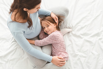 Top view of pregnant woman spending time with little daughter