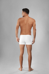 Handsome man in white underwear on light grey background, back view