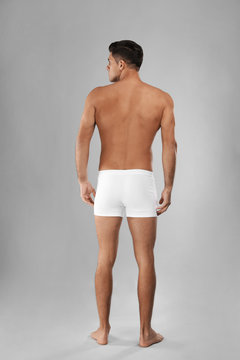 Handsome man in white underwear on light grey background, back view