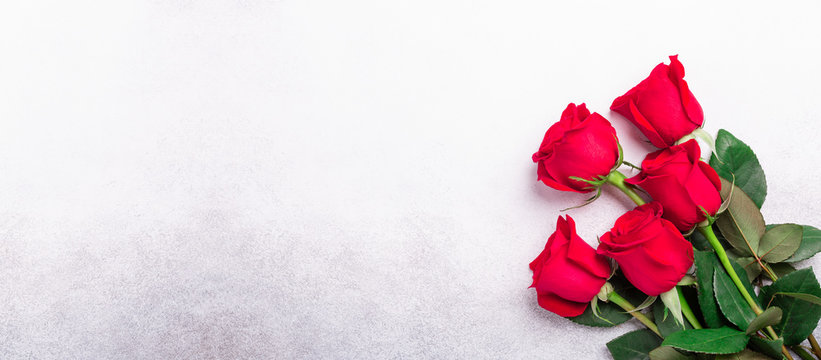 Red roses flowers on stone background. Valentine's greeting card. Top view. Copy space. Web banner