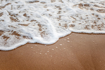Sea, beach, sand, wave, summer, background concept. White waves on a sandy beach in the summer on sunset. Background sea concept.