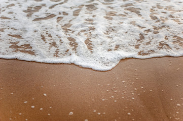 Sea, beach, sand, wave, summer, background concept. White waves on a sandy beach in the summer on sunset. Background sea concept.