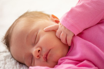 Cute little newborn sleeping with his finger on face