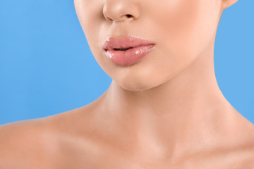 Young woman with beautiful full lips on light blue background, closeup