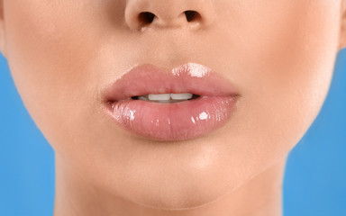 Young woman with beautiful full lips on light blue background, closeup