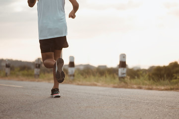 fitness, workout, jogging, exercise, lifestyle and healthy concept. The man is jogging to exercise for his health on the edge of the roadside the sunset.