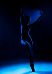 Slim girl wearing a white bodysuit dances a modern avant garde dance, covering her body with...