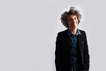 Fototapeta na wymiar Handsome smiling young man, with curly hair, dressed in a jacket, listening to music, put headsome, isolated on a white background. Space for text.