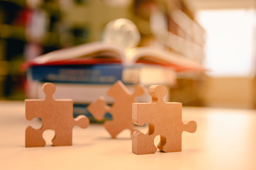 Businessman hands connecting jigsaw puzzle in the library background blur, Success and strategy...
