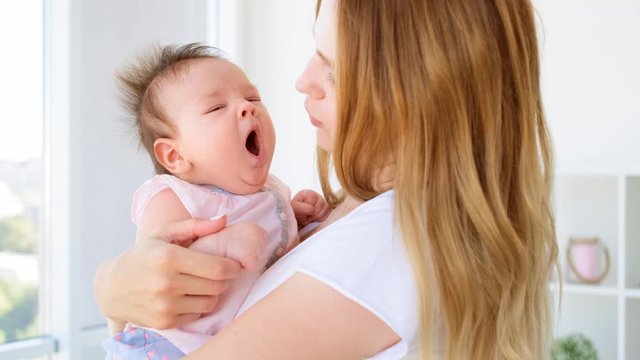 Cute baby yawning in mother's hands