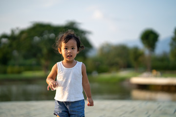 girl standing at park at the pond.