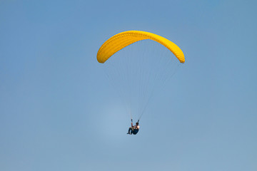 Flight on a yellow paraglider in blue sky