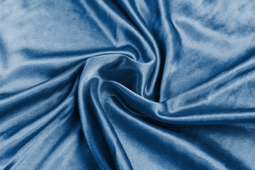 Fototapeta na wymiar Shining classic blue silk atlas satin fabric with folds, fabric waves. Real fabric background. Color of the year 2020